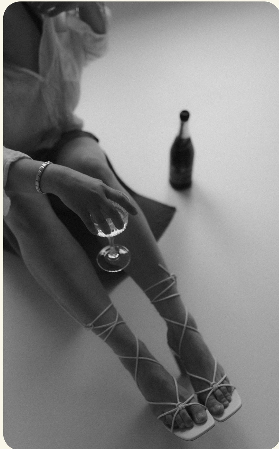 Black and white photo of a person seated on the floor holding a glass